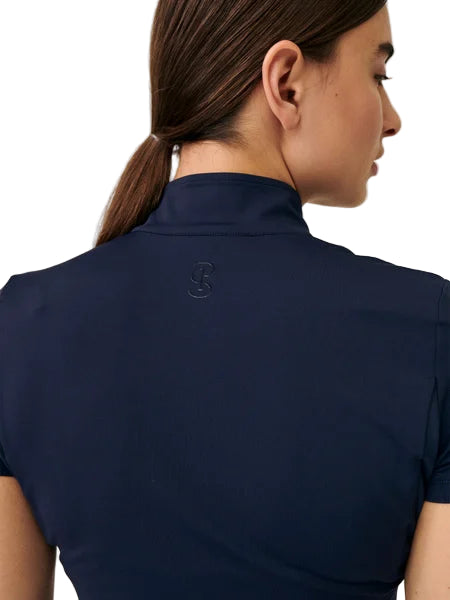 Woman wearing a navy blue polo shirt with a logo on the back against a white background